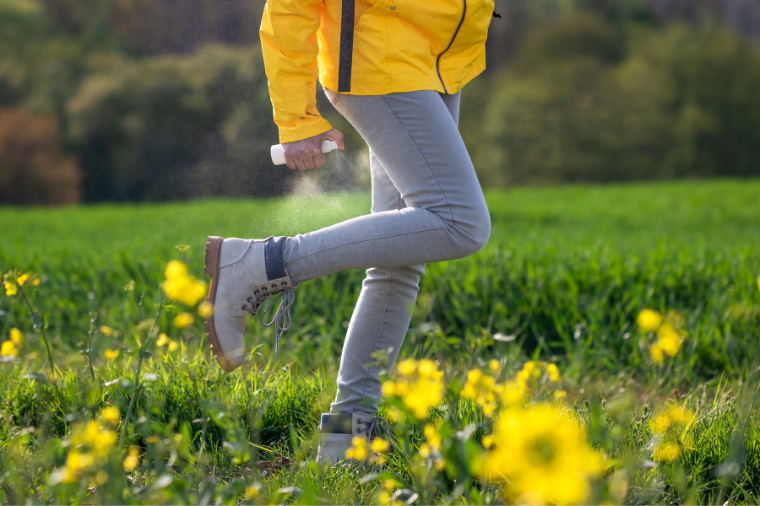 Man spraying tick repellent on his legs