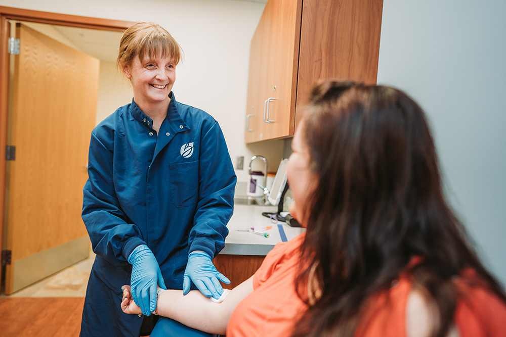 Black River Memorial Hospital lab worker holds a piece of gauze on a patient's arm.